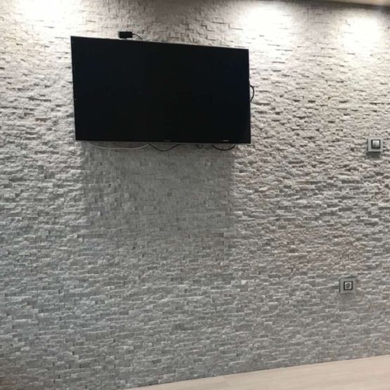 Каменна стена зад телевизор в хола